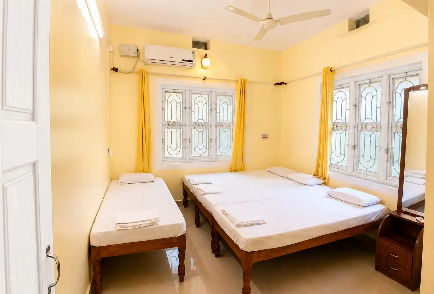Bedroom from doorway with beds, windows and mirror in SriNidhi apartment.