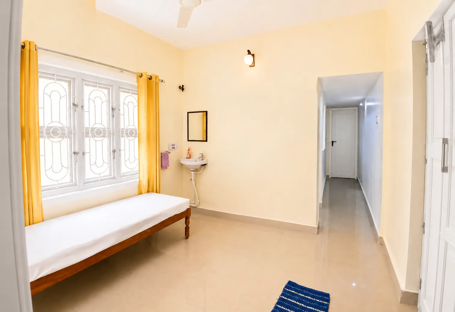 Single bed, washbasin and long passage in SriNidhi apartment.