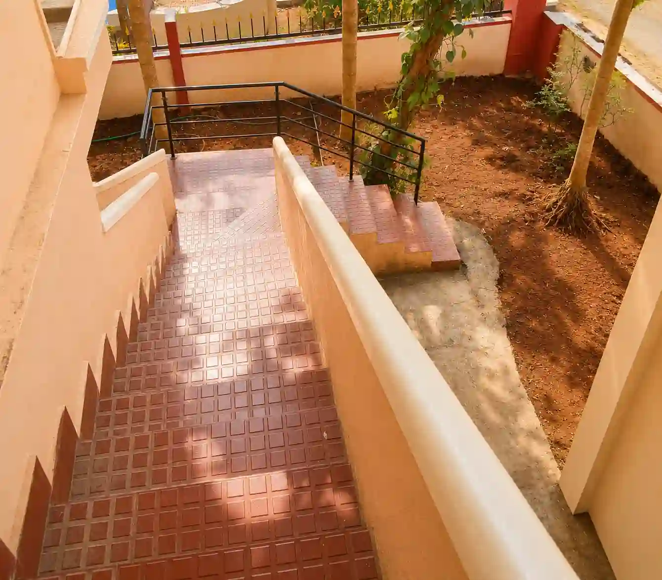 Exterior stairs viewed downward, railings and courtyard at Balakrishna Udupi Homestay.