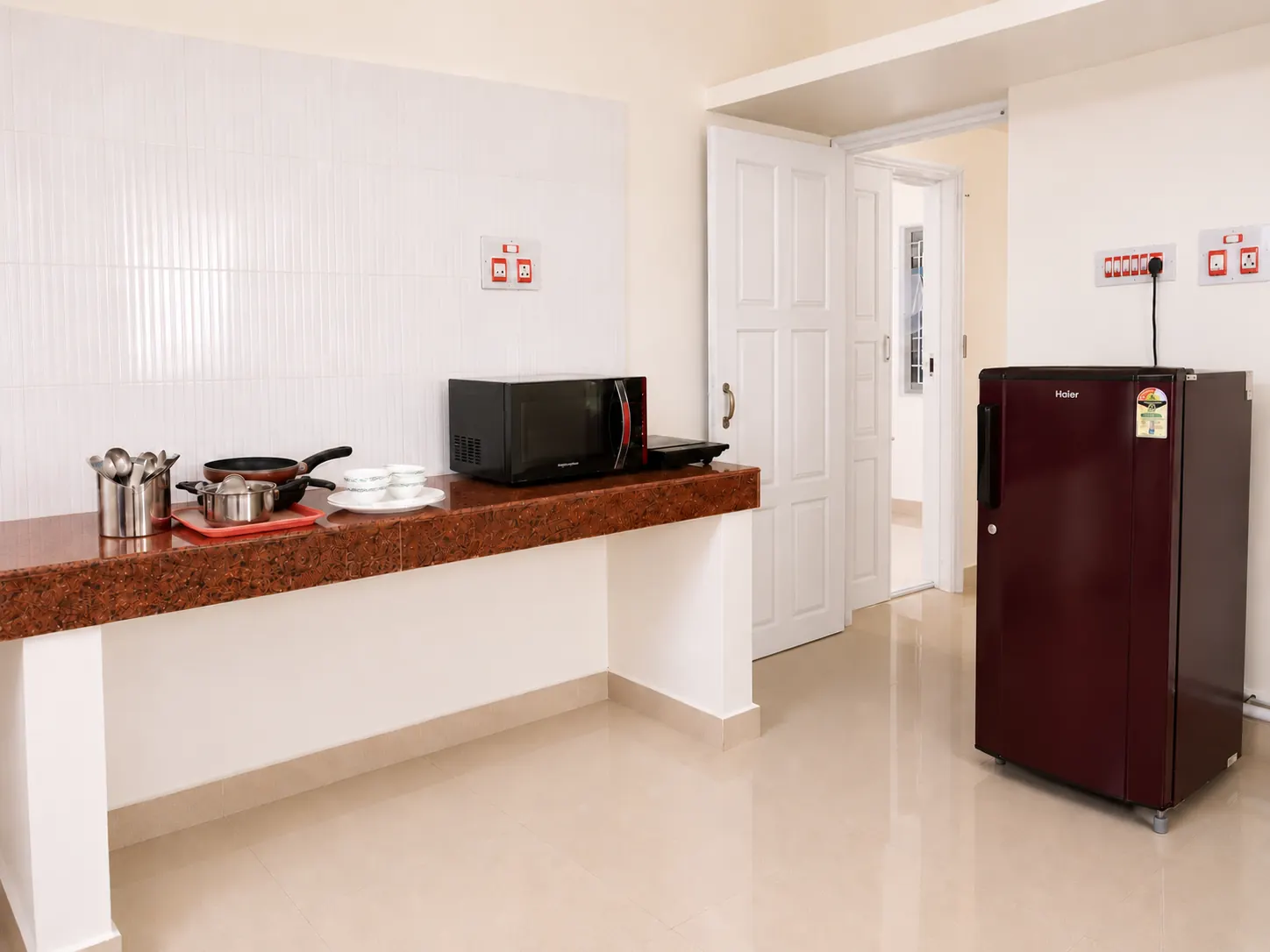 Counter with microwave and cookware, separate refrigerator in Nidhi apartment.