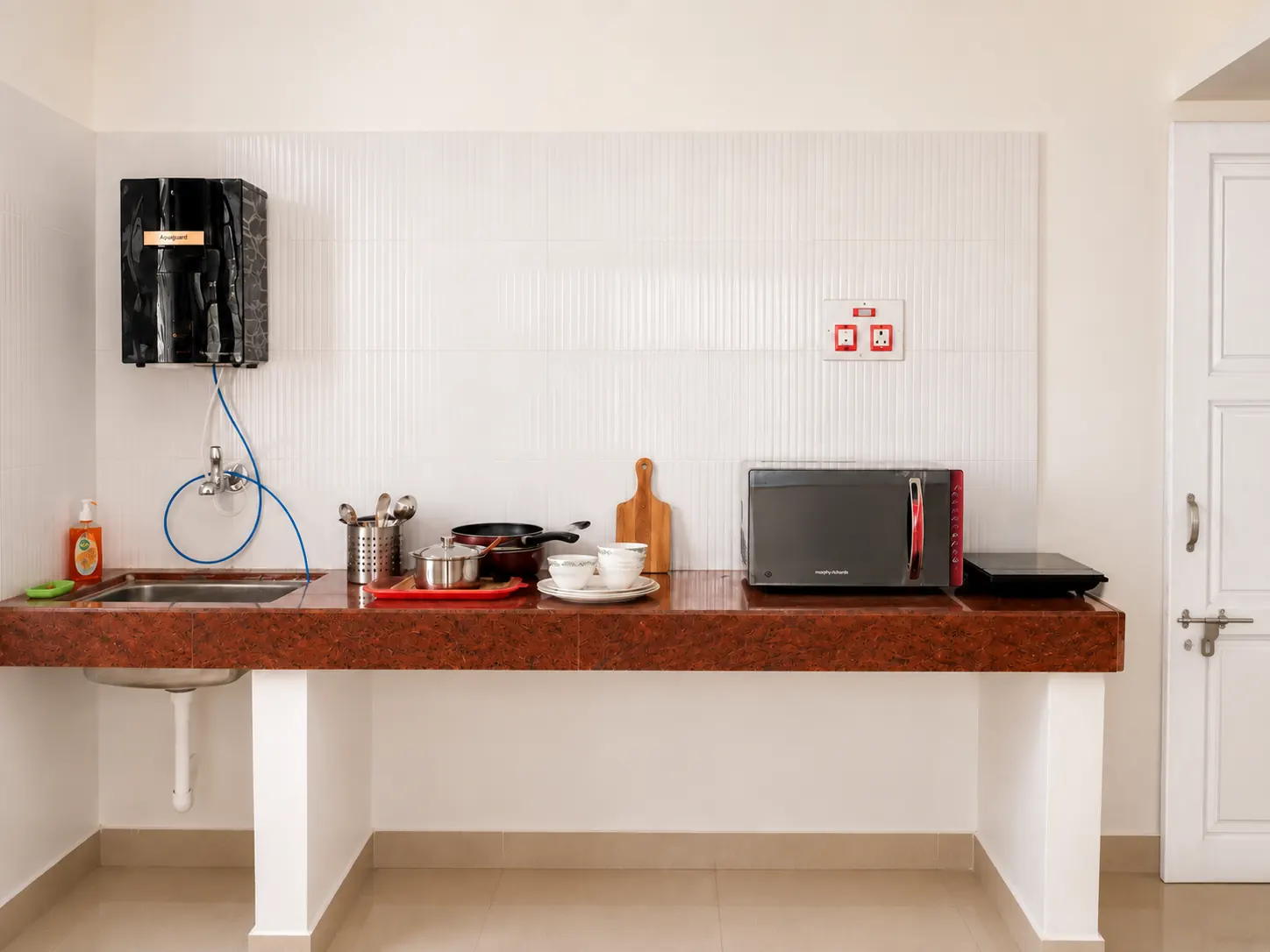 Front view of purifier, counter, cooktop, cookware and microwave in Nidhi apartment.