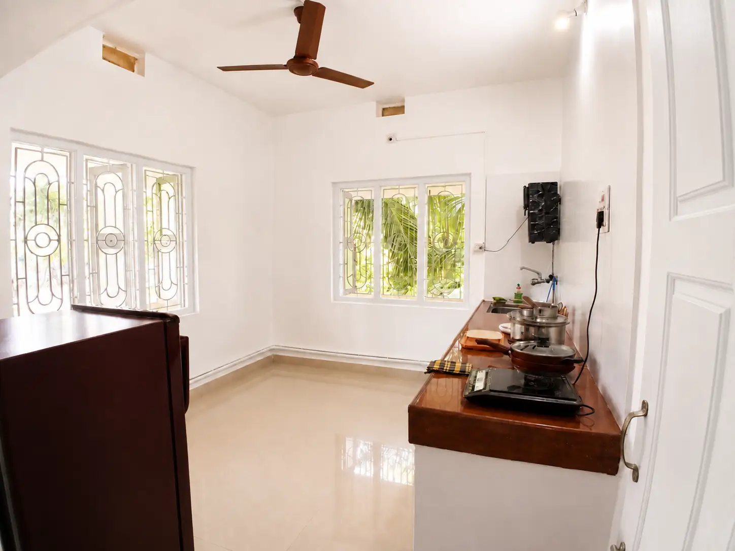 Wide kitchen view with windows and cooking counter in Nidhi apartment.