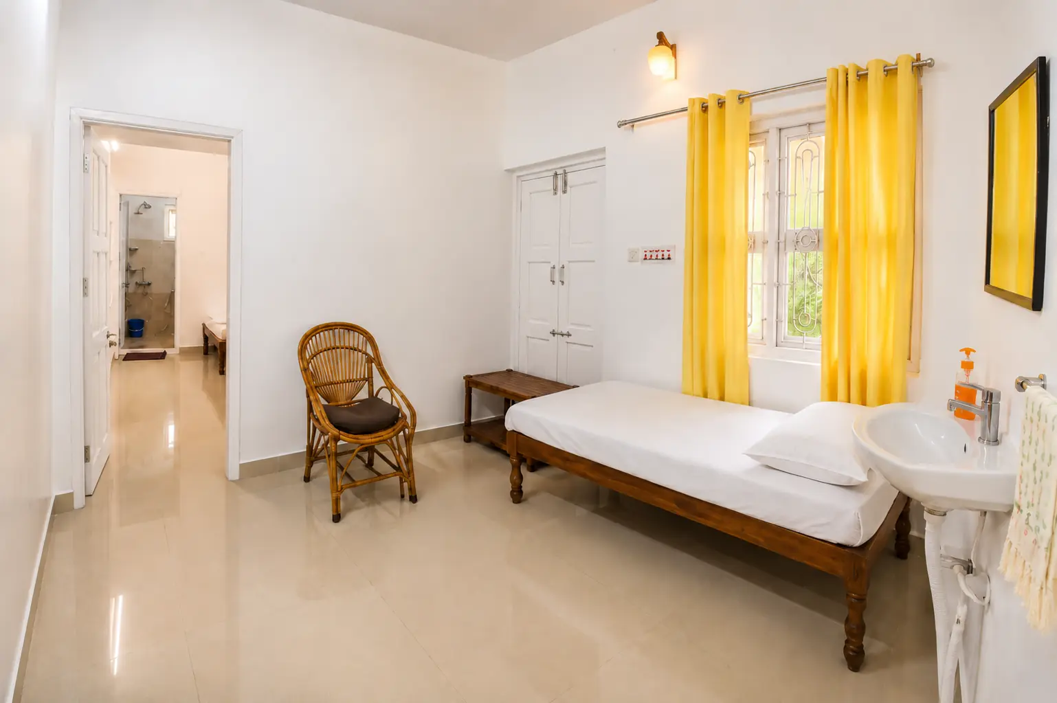 Single bed, chair, washbasin and bedroom doorway in Nidhi apartment.