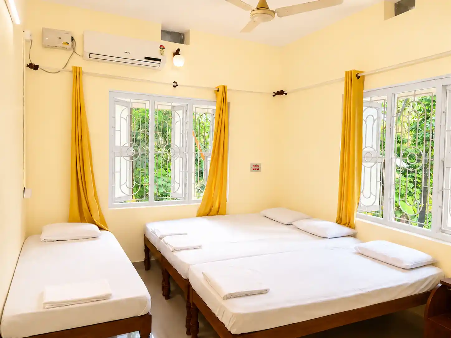 Bedroom with multiple beds, AC and corner windows in SriNidhi apartment.