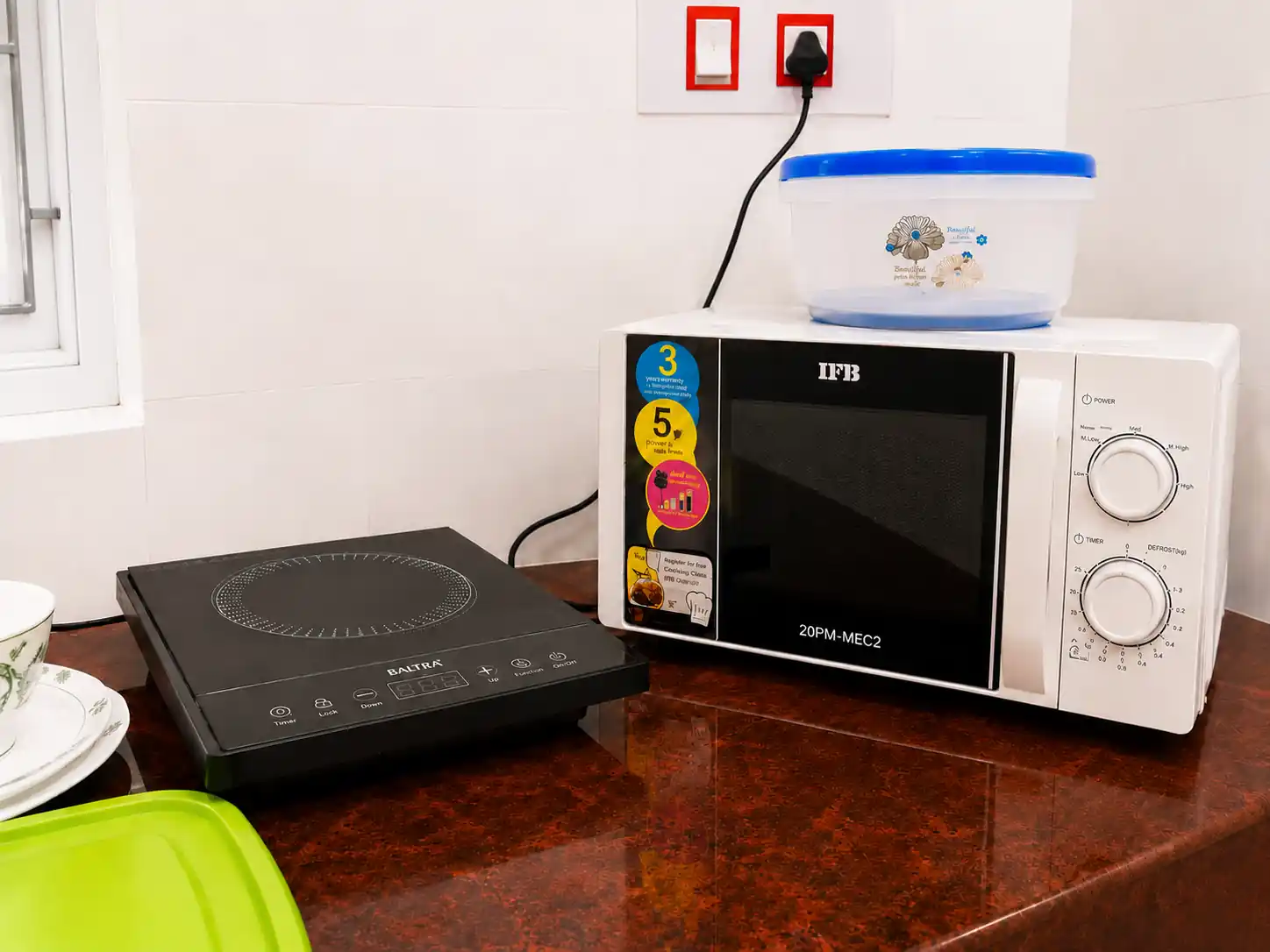 Microwave and induction cooktop on SriNidhi kitchen counter.