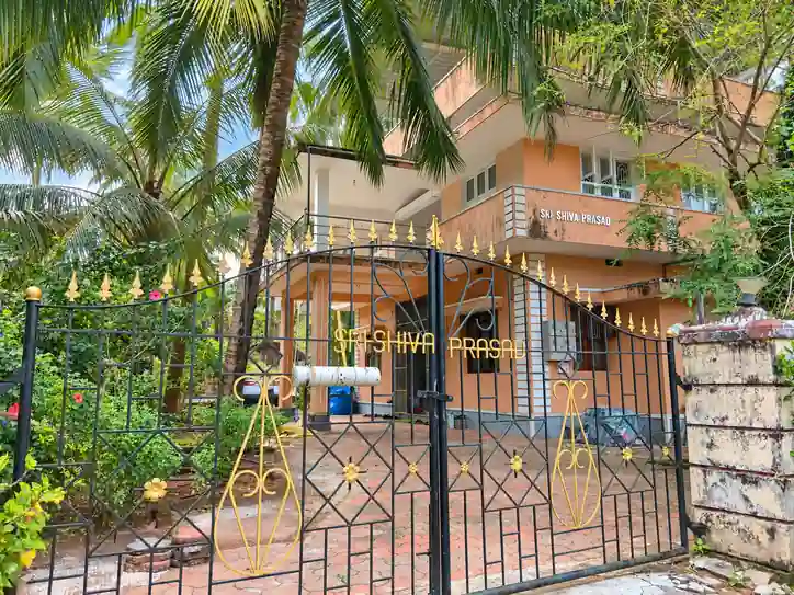 Street-facing gate and partially obscured building; SHIVA PRASAD signage at Balakrishna Udupi Homestay.