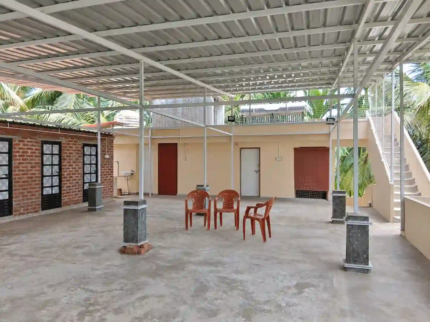 Roofed terrace with four of the six additional shared washrooms visible, plus open space and stairs at Balakrishna Udupi Homestay.